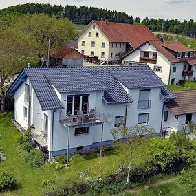 Modernes Einfamilienhaus mit Garten in ländlicher Umgebung und Nachbarhäusern.