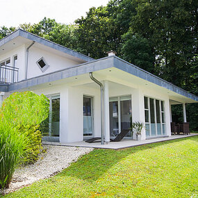 Modernes Einfamilienhaus mit großer Terrasse und gepflegtem Garten am Waldrand.