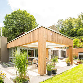 Modernes Einfamilienhaus mit Holzfassade, großer Terrasse und Garten im Grünen.