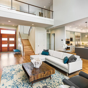 Modernes offenes Wohnzimmer mit Holzboden, Designerküche und großer Fensterfront.